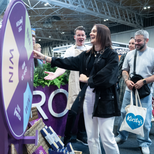 A visitor engaging with a brand's spinning wheel activity at the Allergy & Free From Show